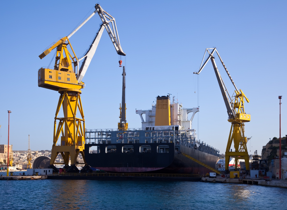 international freight forwarder USA export — cargo vessel at commercial port with loading cranes