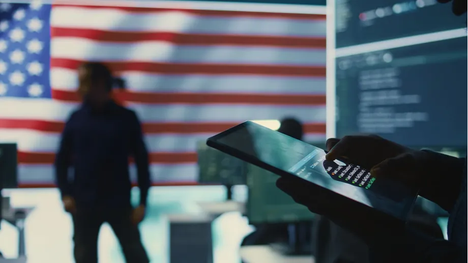 Customs expert using digital tablet to process import documents with American flag in background - solution for CBP import delays.