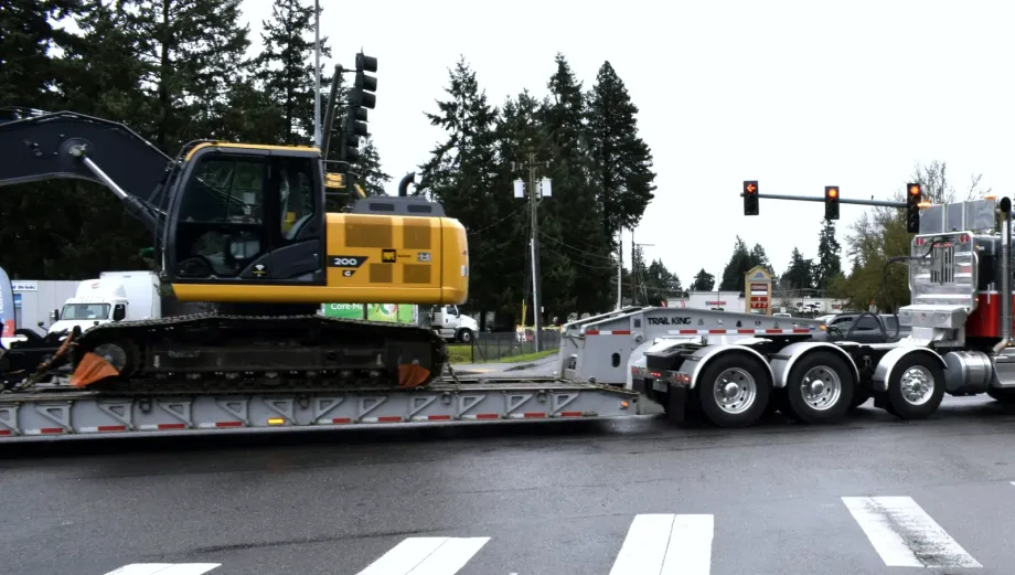 Excavator on a lowboy trailer during US sourcing and export inland transport